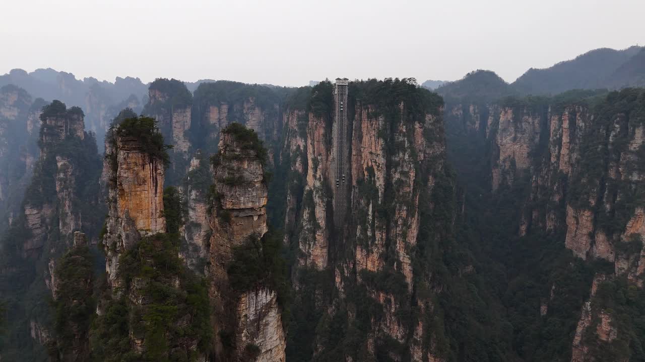 Towering pillars and cliffs define Zhangjiajie’s iconic landscape, featuring the Bailong Elevator, an engineering marvel that scales these dramatic sandstone formations for unparalleled views.