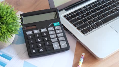 portátil, calculadora y papeles en un escritorio