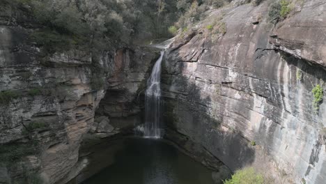 Water plunges from rocky cliffs into a tranquil pool, creating a breathtaking spectacle of nature's power and beauty at la foradada waterfall in catalonia