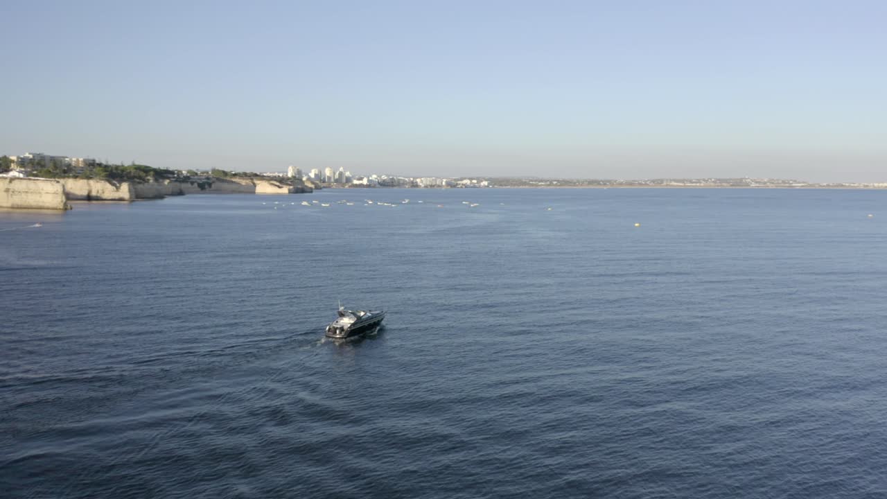 A Deluxe Yacht Sailing And Leaving Wake On The Deep Blue Sea In Albufeira, Portugal On A Summer Day - aerial drone, orbiting shot