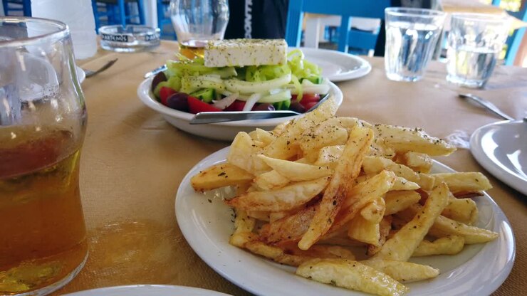 Hand-held Footage Of A Freshly Prepared Greek Salad And A Plate Of Chips, Served Within A Outside Restaurant