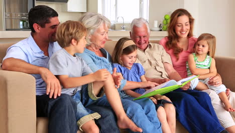 extended family looking at photo album together on couch