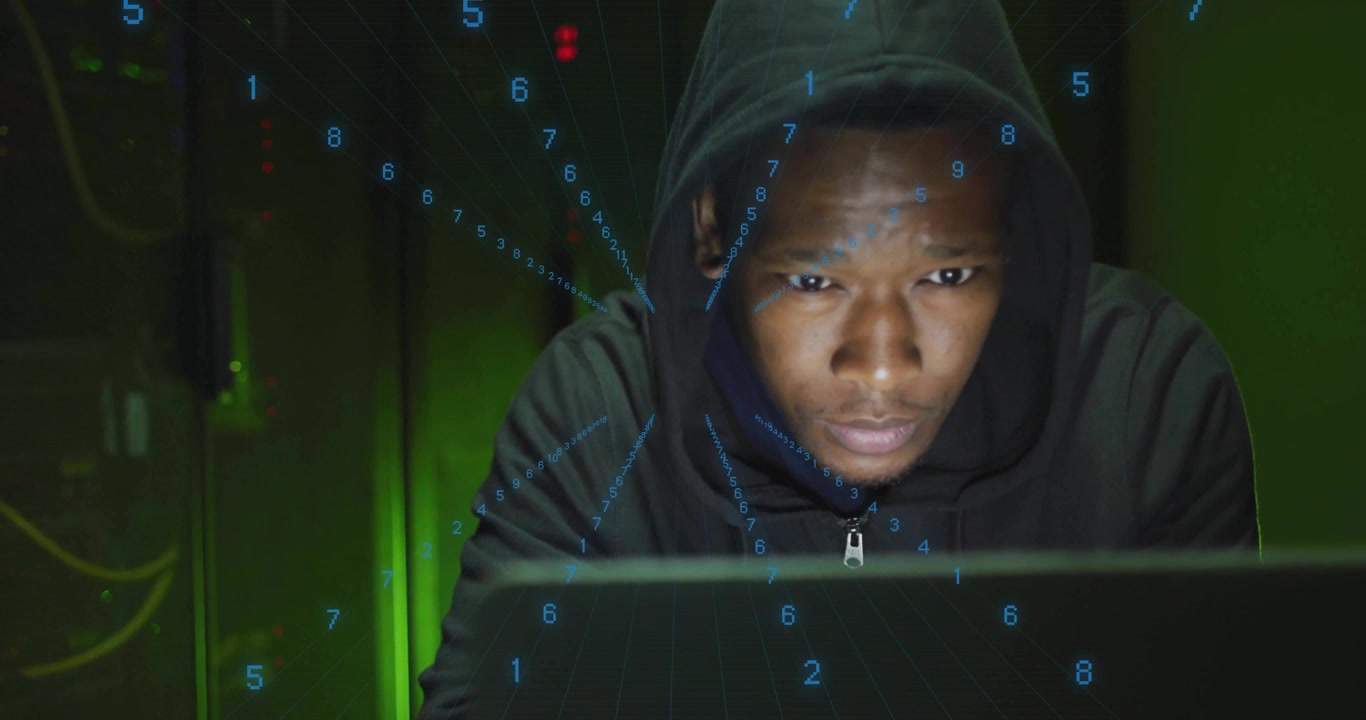 Homme assis derrière un ordinateur portable, tournant la tête, alerté par une superposition de code numérique en flux continu dans un centre de données.