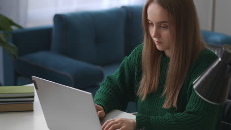 Una-Mujer-Joven-Está-Chateando-En-Línea-En-Las-Redes-Sociales-Escribiendo-Una-Computadora-Portátil-Y-Enviando-Mensajes.-Retrato-De-Una-Joven-En-La-Mesa-De-La-Habitación-Comunicándose-En-Internet.