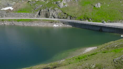 mountain road in the swiss alps, passing by a deep blue lake