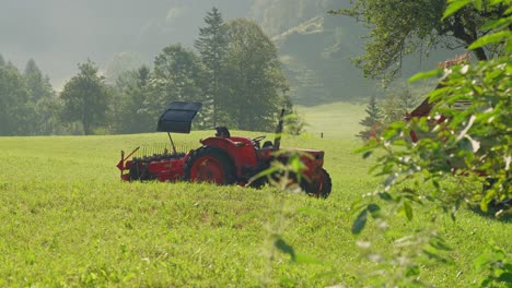 a red tractor in a green meadow on a sunny day, surrounded by trees and hills