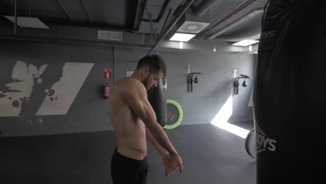 joven atlético estirando los brazos después de hacer ejercicio en el gimnasio