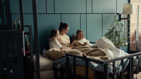 a trio of girls lie on the bed with their light colored dog and chat. modern bedroom with turquoise colors