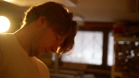 Close-up-of-a-young-blonde-long-haired-man-using-the-hammer-in-his-workshop