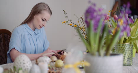 mujer joven que usa el teléfono inteligente durante el desayuno de pascua