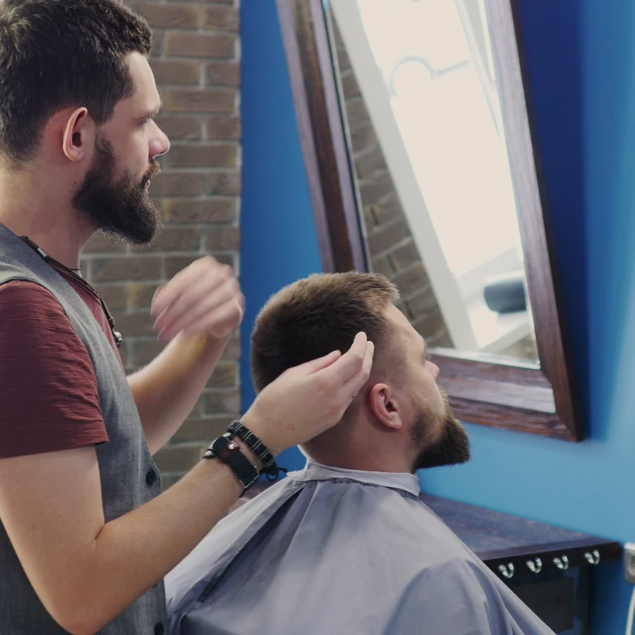 Barber påfører produkt i kundens hår i barbersalon