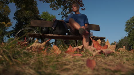 Low-angle-wide-shot-of-a-cyclist-sitting-on-a-park-bench-admiring-the-view