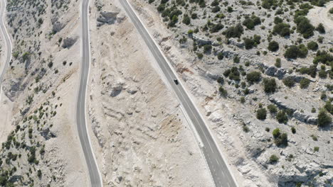 wide drone shot of two dune buggies descending large empty mountain roads