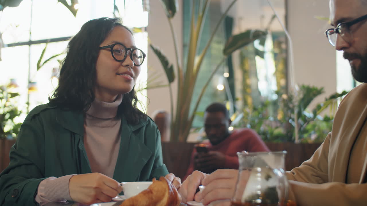 카페에서 동료와 대화를 나누고 차를 마시는 아시아 여성