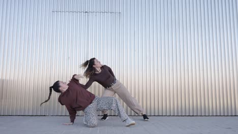 two young women dancing a choreography in urban environment