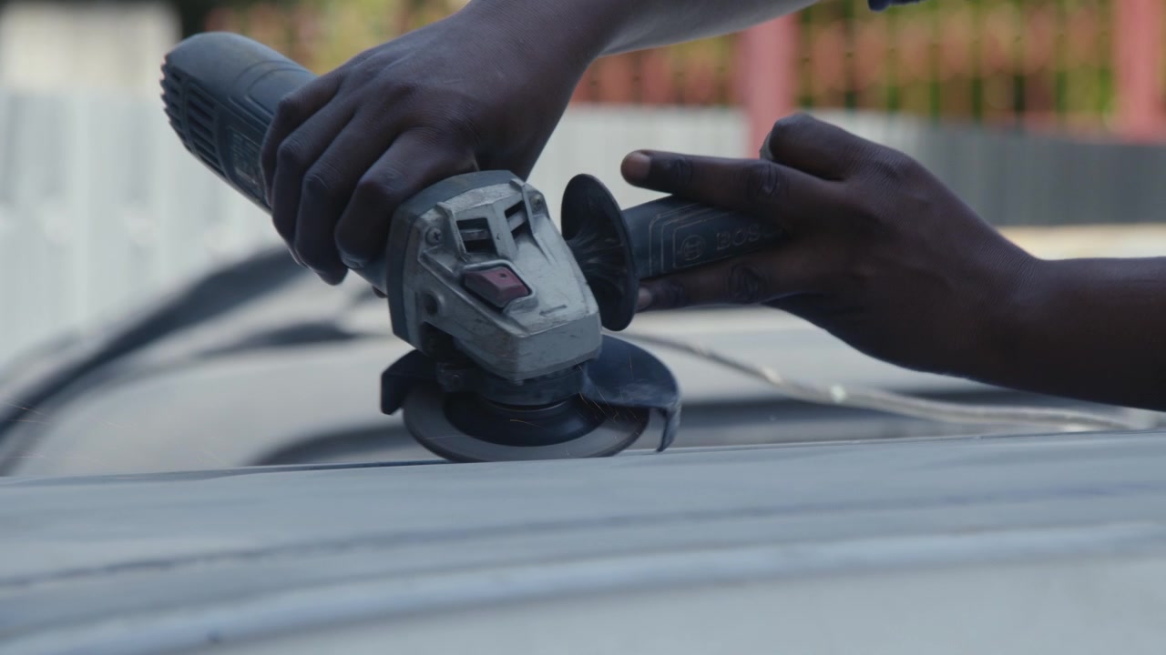 African Person doing Vehicle Body Work using Grinder
