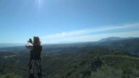 descenso aéreo de una mujer vestida de gimnasio hablando en video con alguien en las montañas