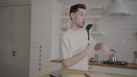 man singing in kitchen with a spoon