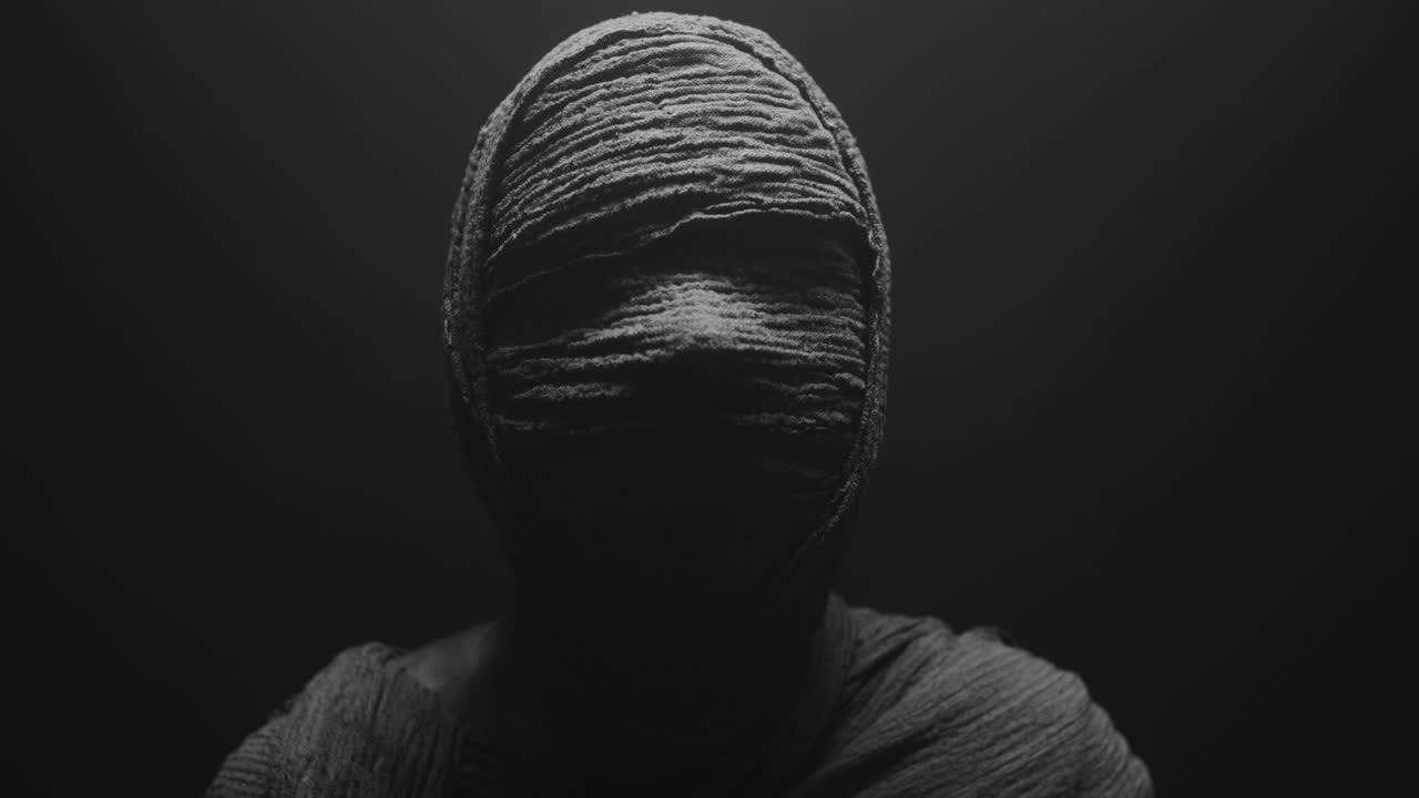 A mummy of a woman on a dark backdrop rises  and then turns her head