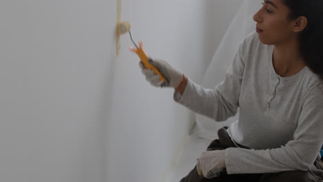 mujer pintando una pared de amarillo
