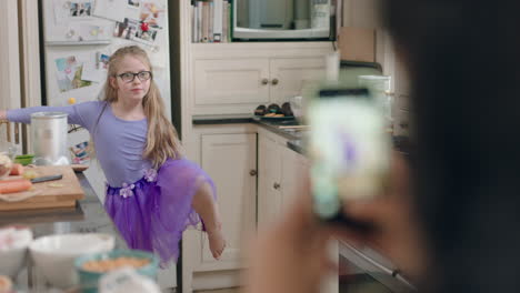 Madre-Tomando-Fotos-Usando-Un-Teléfono-Inteligente-De-Una-Hija-Pequeña-Posando-Usando-Un-Lindo-Tutú-De-Bailarina-Mostrando-Un-Cuerpo-Flexible-Disfrutando-Del-Ballet-En-Casa