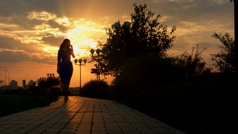 girl walks away and turnes back at the sunset