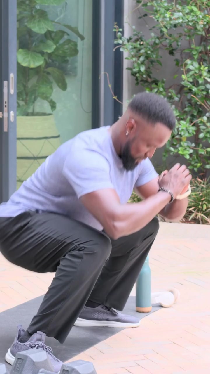 Vertical video: Stepping onto mat, man doing lunges and squats on patio, grabbing bottle to drink