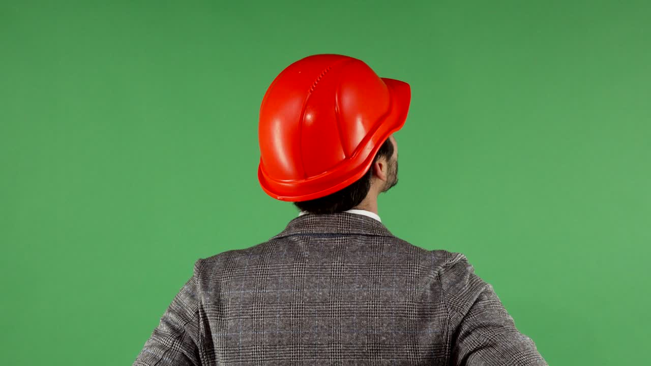 Rear view portrait of a contractor wearing hardhat looking at the green screen