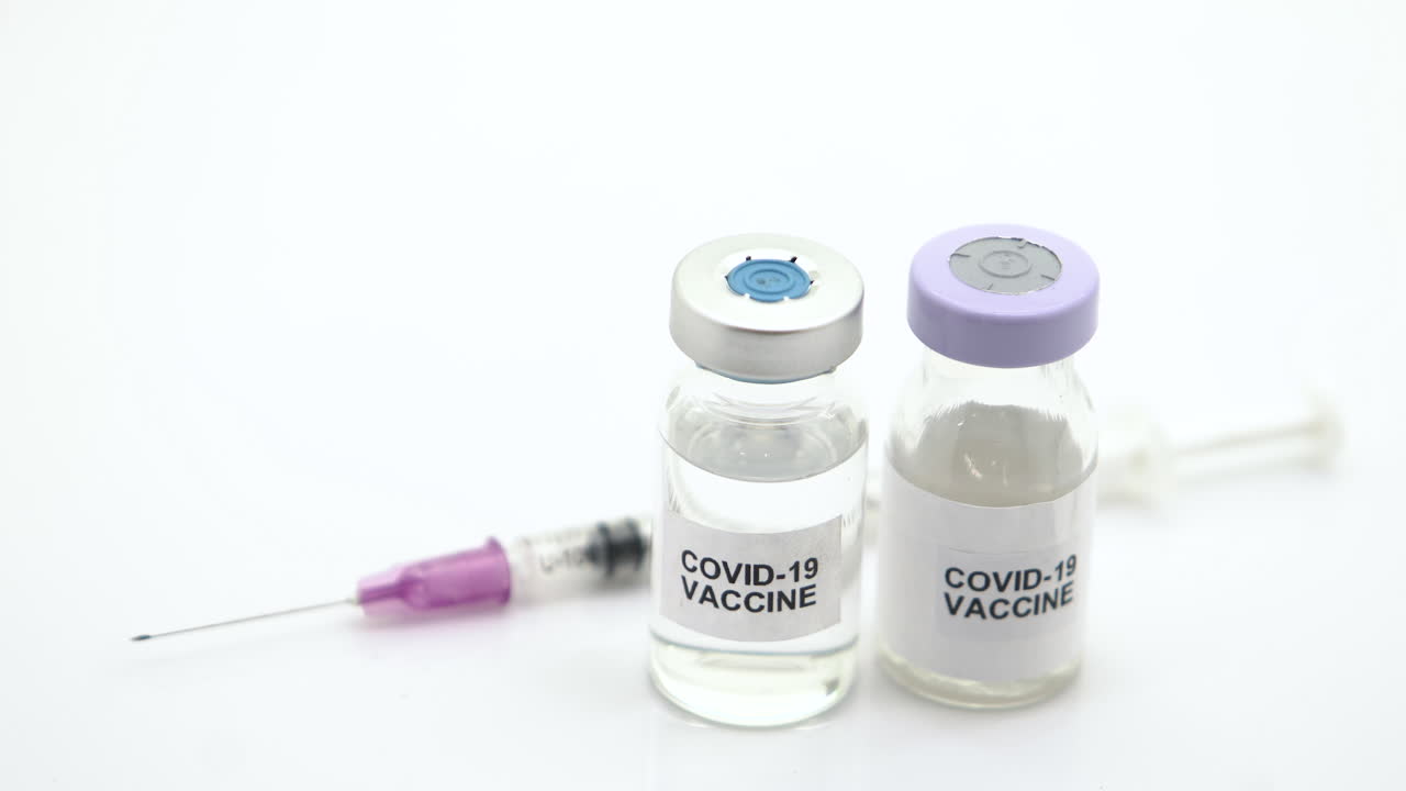 The vaccines and syringes are used to prevent vaccination from COVID-19 on a white background. The camera moves from right to left.