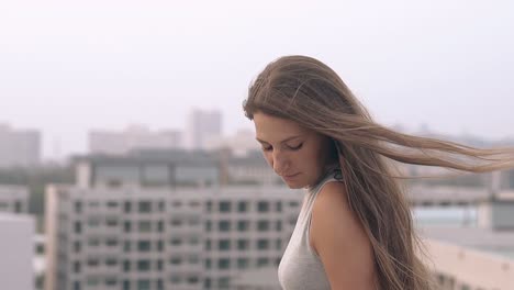 chica feliz en vestido gris posa en el techo al atardecer en cámara lenta
