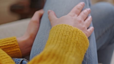 woman sits home in comfort, sliding hands over leg