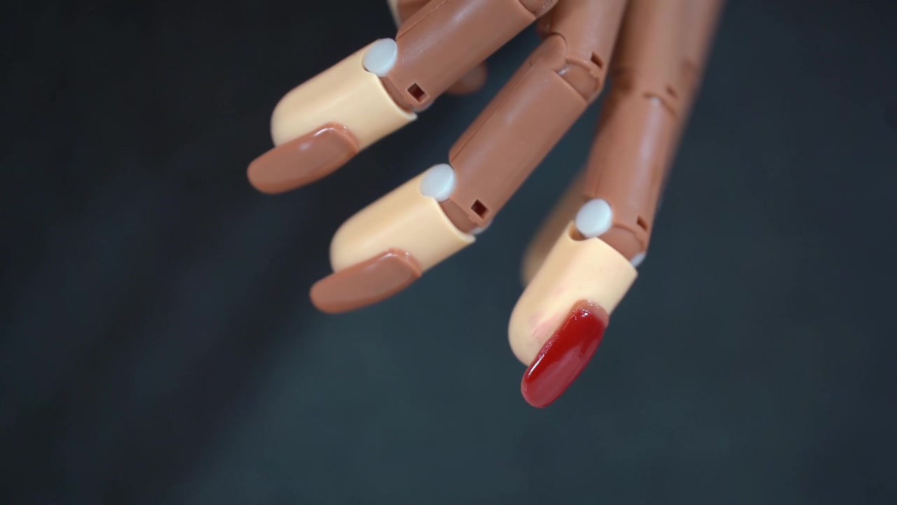 Mani femminili dipingono con smalto rosso unghie finte incollate a una mano protesica 4k