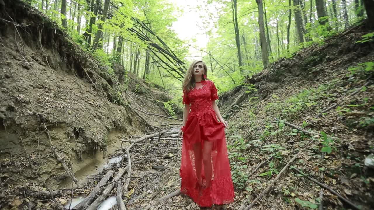 Girl Lost In Forest. Steadicam footage of a girl in long red dress lost in forest