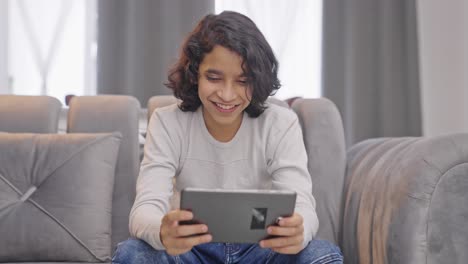 Happy-Indian-kid-boy-watching-videos-on-tablet