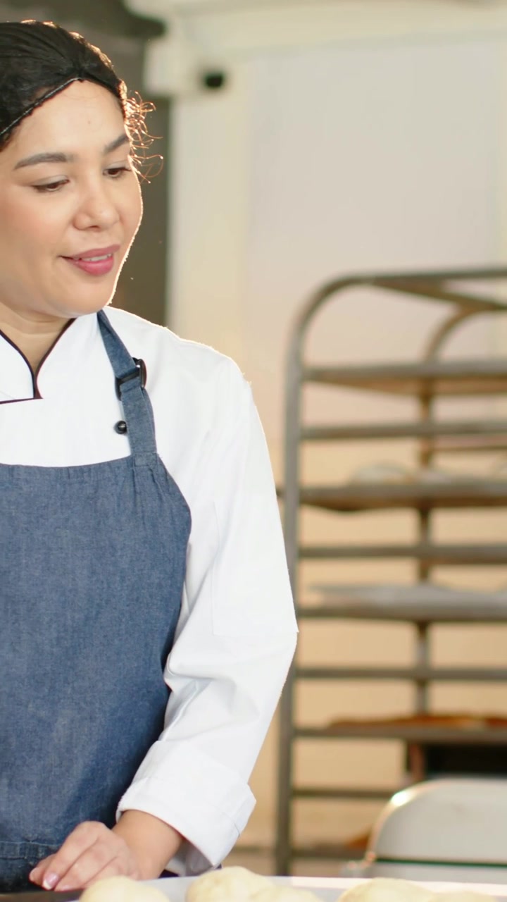Vídeo vertical: Observando o chef à esquerda fazendo massa após um colega raspar na padaria, jaleco, espaço para texto.
