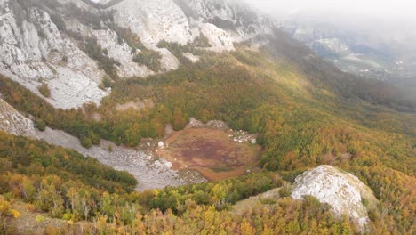 Aerial-footage-of-the-Lovcen-National-Park-and-Black-Lake-with-amazing-fall-colors-everywhere-with-low-clouds