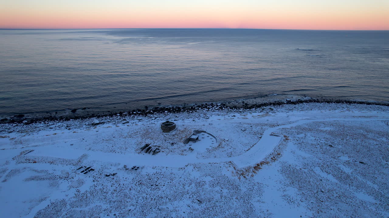 Cinematic 4K drone 360 degree orbit around the historic WWII radar ruins in Eggum. Dramatic winter coastal landscape at sunrise blue hour in the Arctic Lofoten islands