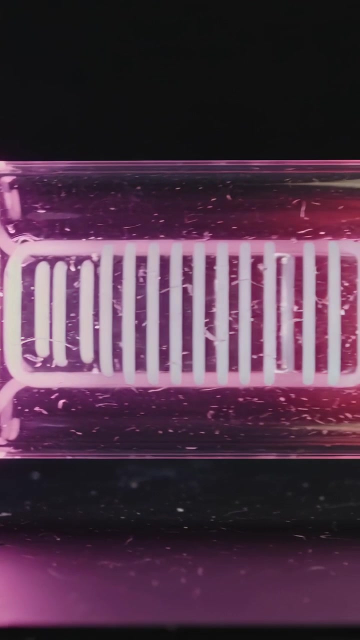 Vertical video: Panning camera after shift revealing clear glass tube in studio, showing pink rods