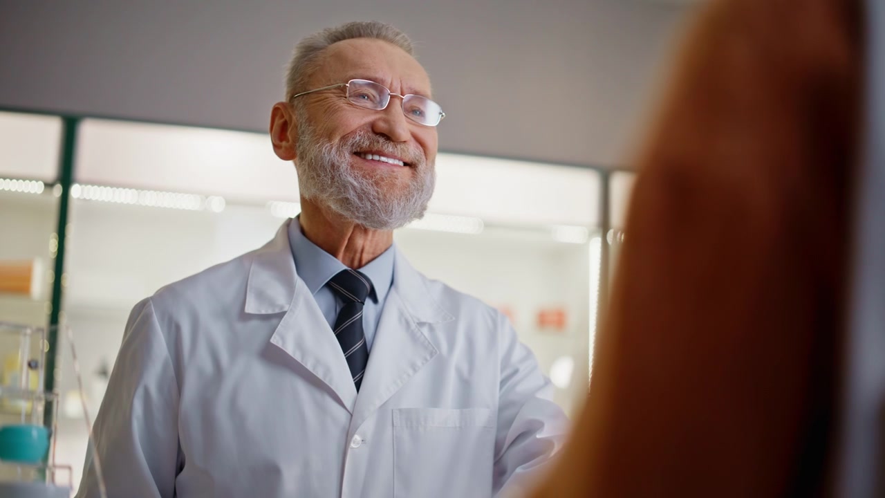 Elderly pharmacist scanning pills serving client closeup. Man selling tablets