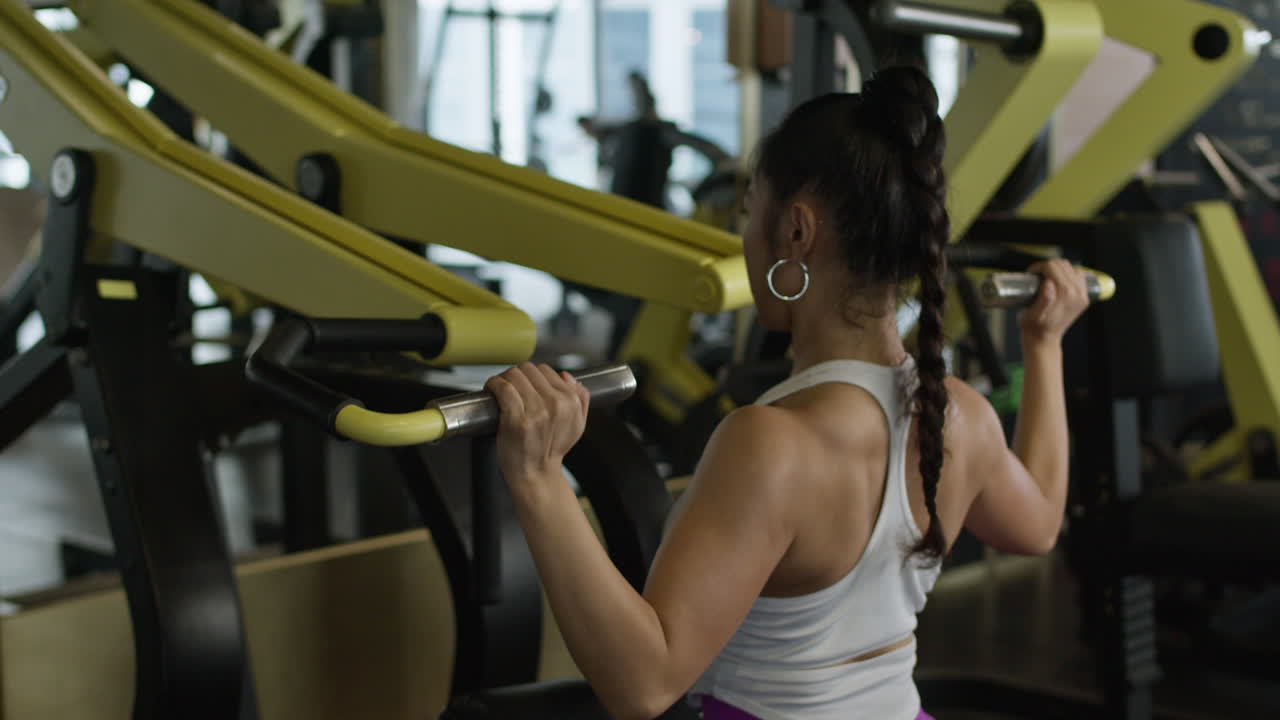 Fitgirl training upper back muscle in gym, steady workout shot from the back