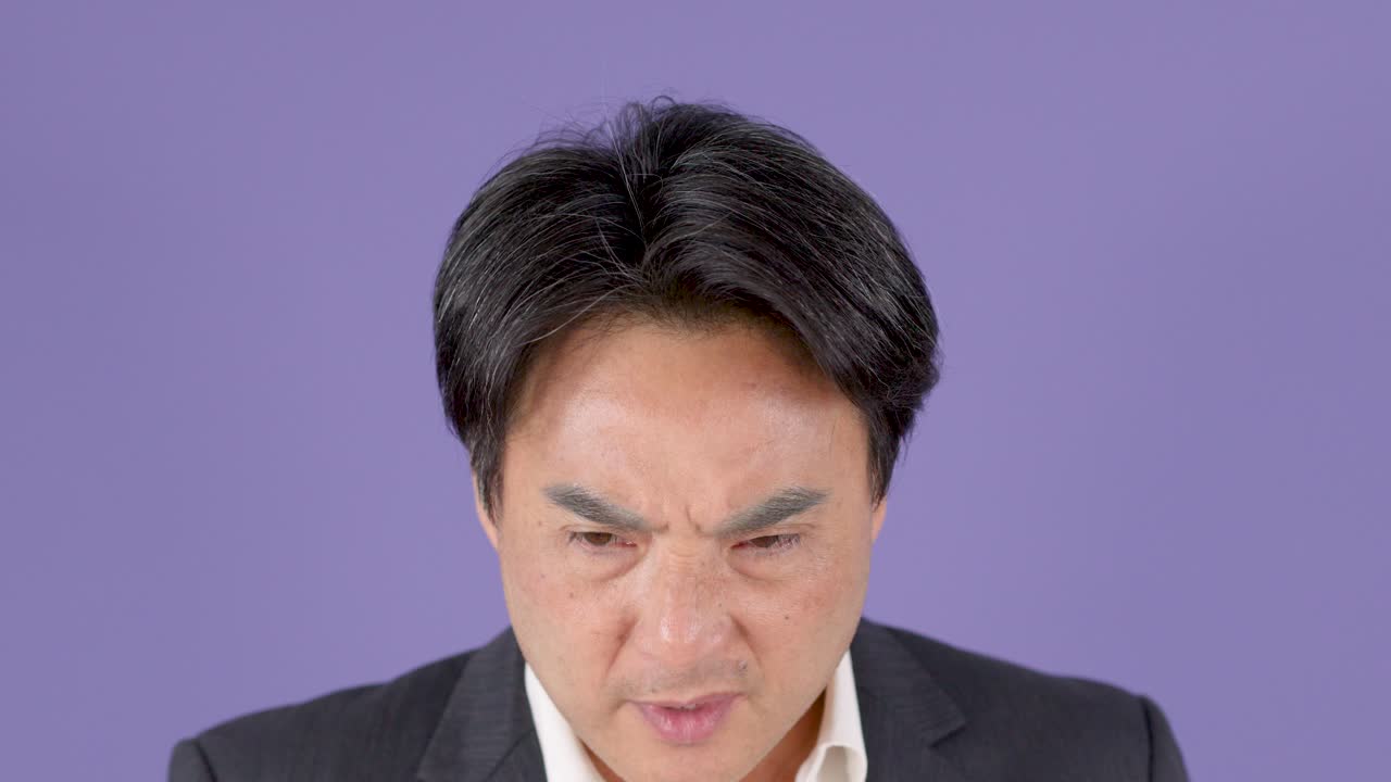 スーツを着た中年ビジネスマンが、強烈な驚きと豊かな表情で反応している、紫色の背景。