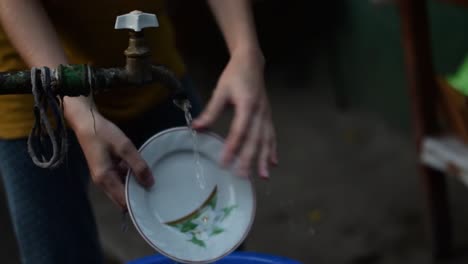 girl washing dishes at a tap