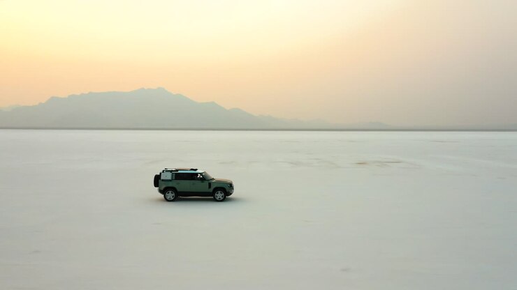 SUV che attraversa le Bonneville Salt Flats con un tramonto vibrante nel cielo dello Utah.