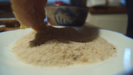 la mano sumerge la carne de schnitzel en un tazón de harina para cocinar, de cerca