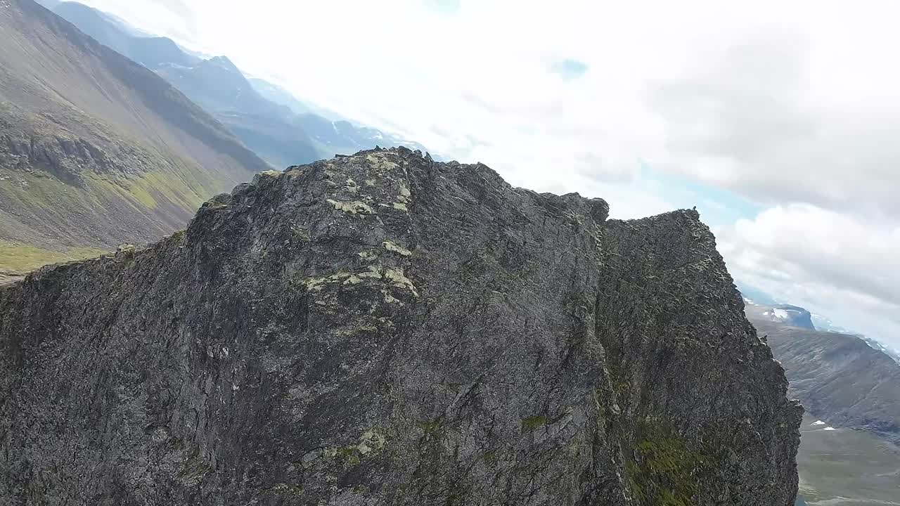 el dron fpv se embarca en un ascenso épico, conquistando una montaña imponente, luego se sumerge emocionantemente en su cara vertical, desafiando la gravedad en un estilo impresionante.