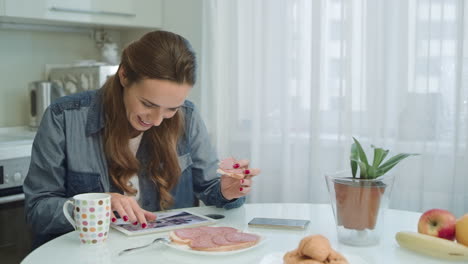 mujer usando la tableta en el desayuno. ama de casa teniendo un almuerzo de nutrición en casa.
