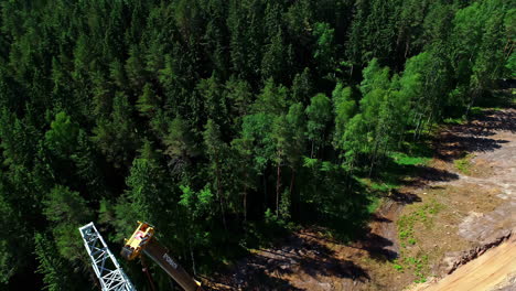 Die-Drohne-Darüber-Und-Der-Aufschlussreiche-Hochspannungsturm-Mit-Arbeitenden-Ingenieuren-Und-Einem-Daran-Befestigten-Kran-Mitten-Im-Wald