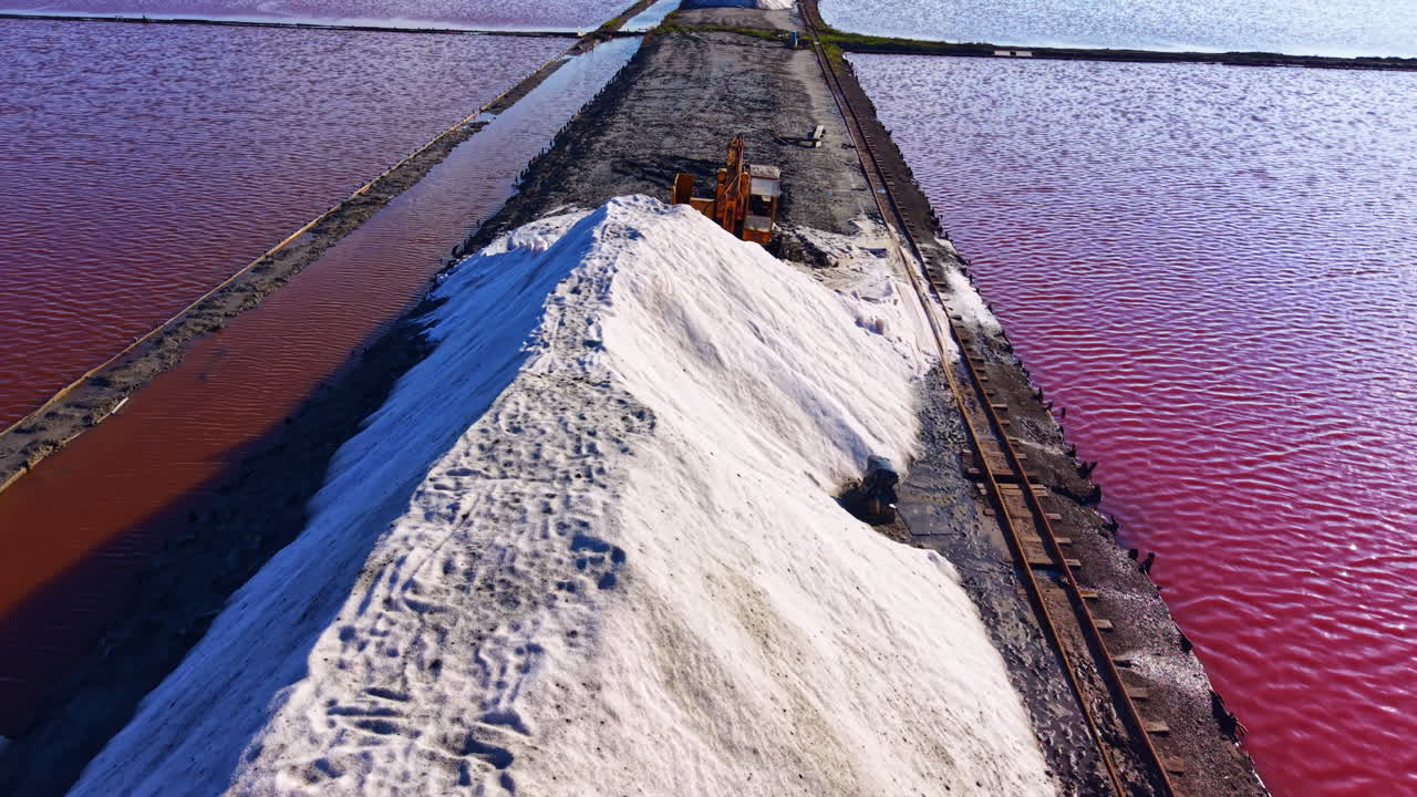 Et glitrende saltbjerg står stolt i livlige saltsletter under en klar, blå himmel i skumringen