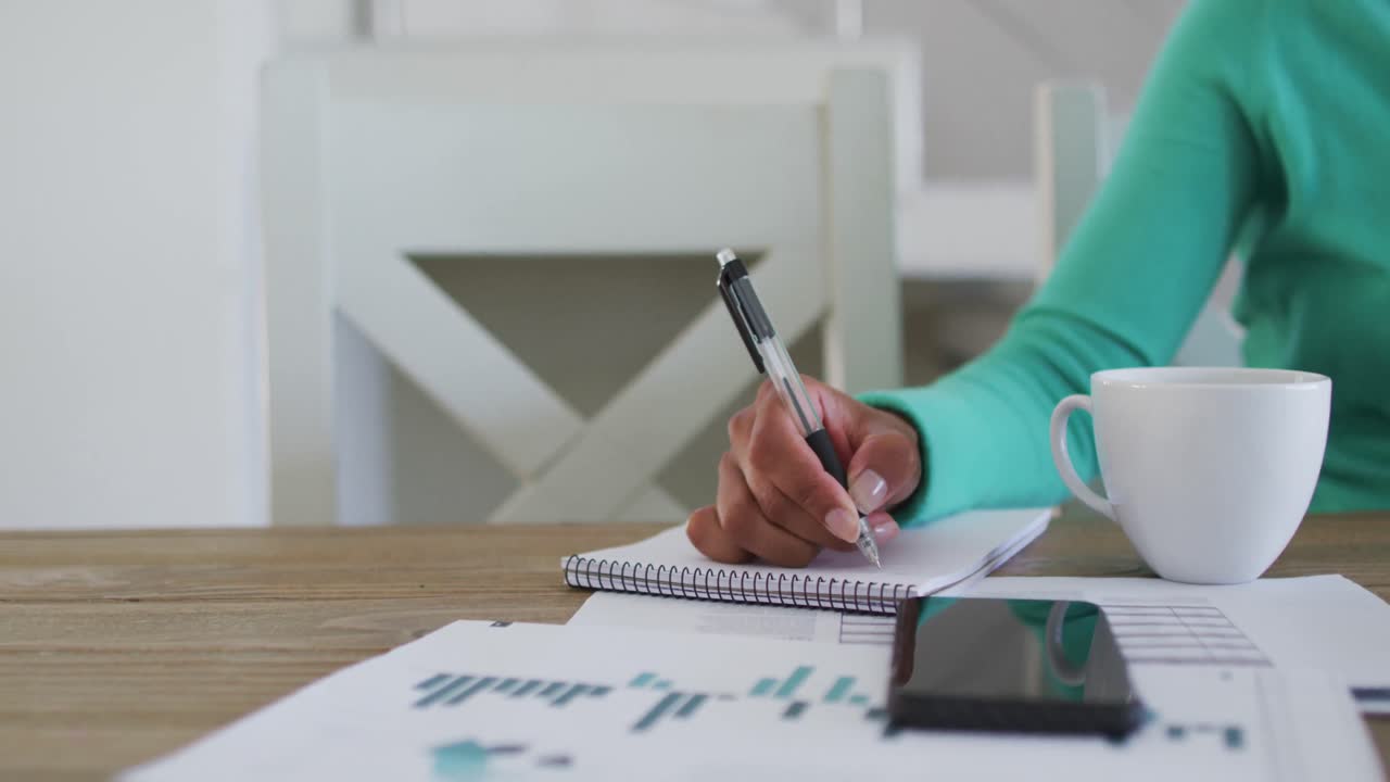 sección media de una mujer afroamericana tomando notas mientras trabaja desde casa