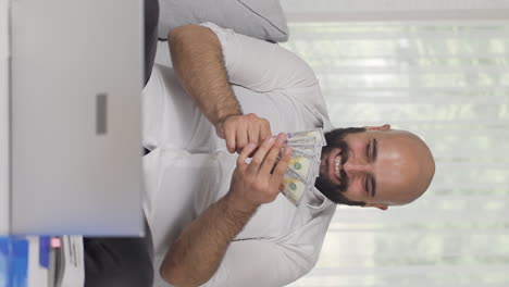 Vertical-video-of-Home-office-worker-man-counting-money-funny-and-funny.